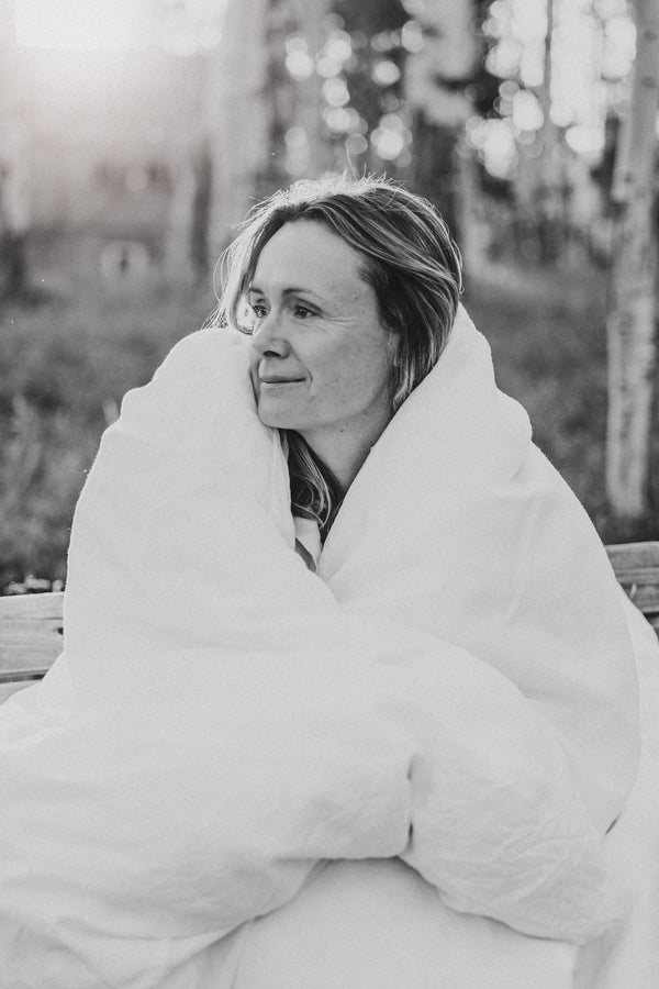 A woman wrapped in a linen sheet among aspens, in black and white