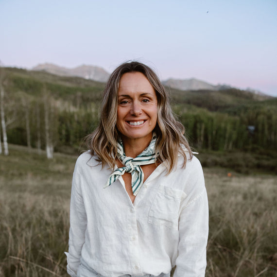 A woman in a white linen shirt standing in a high meadow