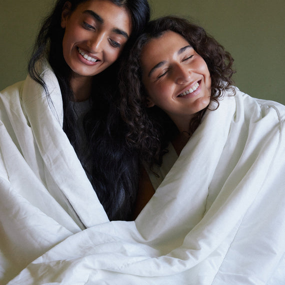 Two people wrapped together in a linen sheet, laughing