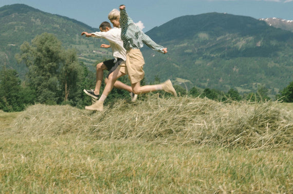 Two people running downhill through dry summer grass