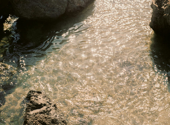 Sunlight breaking across shallow water over stone