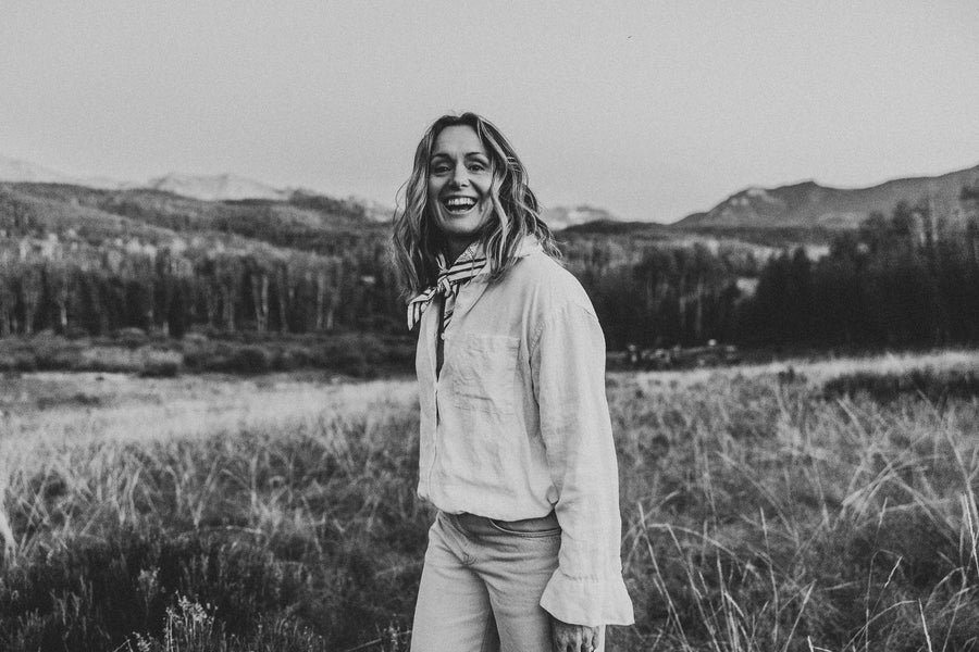 A woman in a linen shirt laughing in high open country.